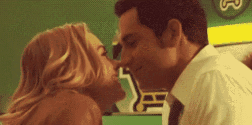 a man and a woman are kissing in a room .