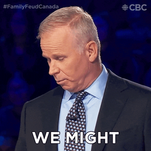 a man in a suit and tie says we might in front of a crowd