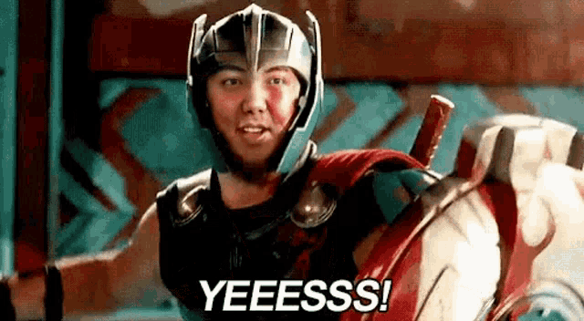 a man in a superhero costume is holding a sword and saying yeesss .