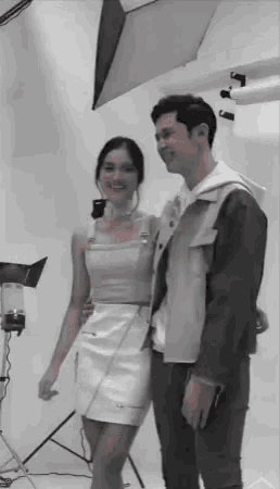a man and a woman are posing for a photo in a photo studio