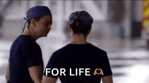 a man and a woman are standing next to each other with the words `` for life '' written on the back of their shirts .