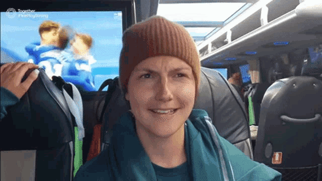 a woman wearing a beanie is smiling in front of a screen that says together on it