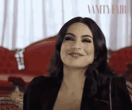 a woman is smiling in front of a vanity fair poster