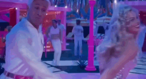 a man and a woman are dancing in a pink room in a video .