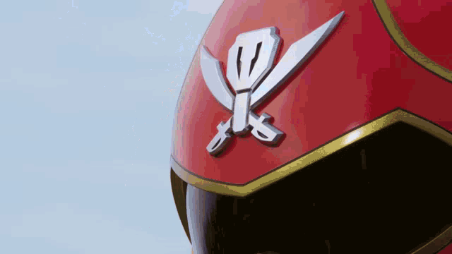 a close up of a red helmet with a crossed sword on it
