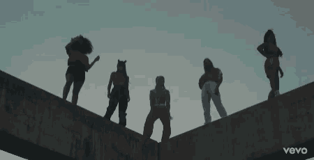 a group of women are standing on top of a concrete bridge .