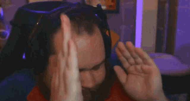 a man with a beard wearing headphones and a red shirt is sitting in a room .