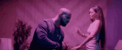 a man and a woman are standing next to each other in a room in a purple light .