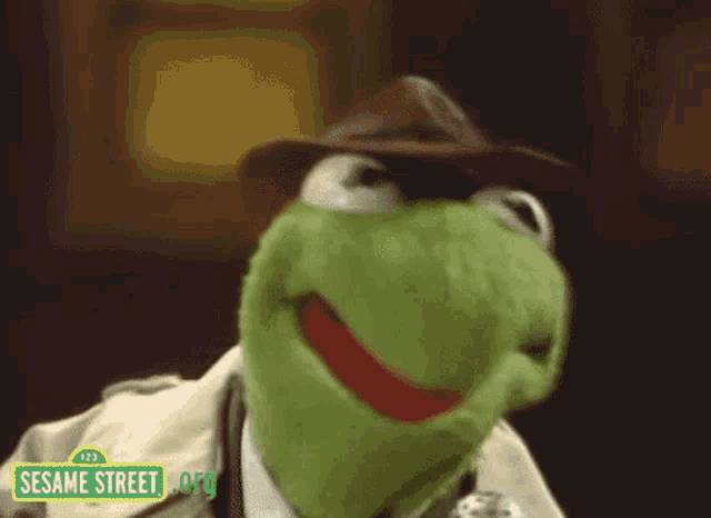 kermit the frog from sesame street wearing a hat and a trench coat