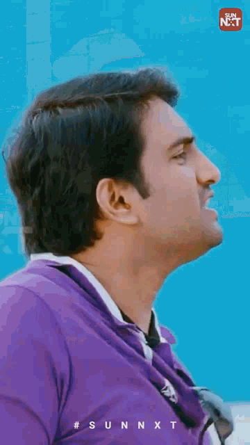a man wearing a purple shirt and sunglasses is making a funny face