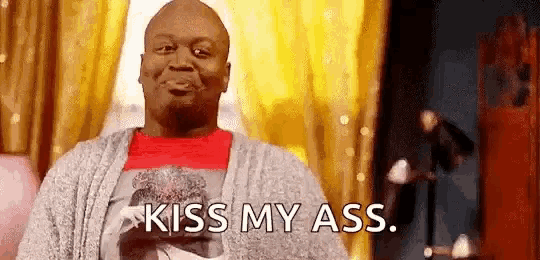 a man is standing in front of a window with the words `` kiss my ass '' written on his face .