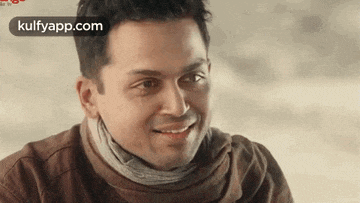 a man with a scarf around his neck is smiling .