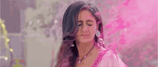 a woman in a pink dress is standing in front of a pink powder cloud .