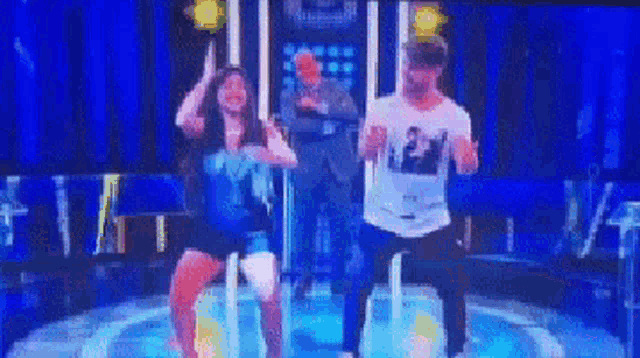 a group of people are dancing on a stage in front of a blue background