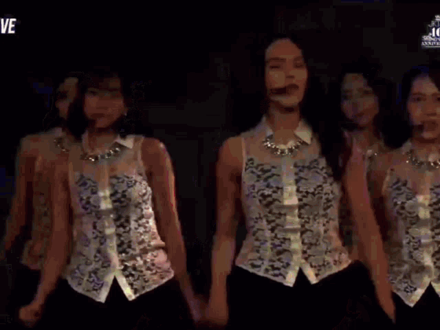 a group of young women are dancing on a stage and the word ve is on the bottom right