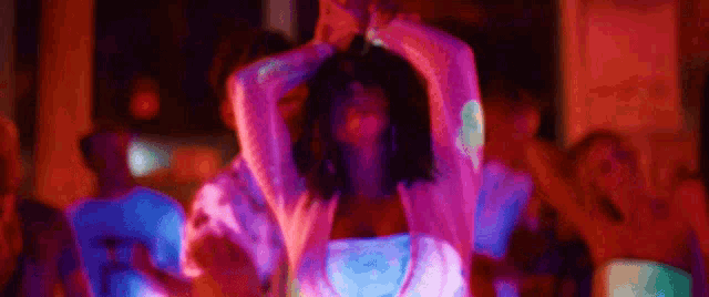 a woman in a glow in the dark dress is dancing in front of a crowd at a party .