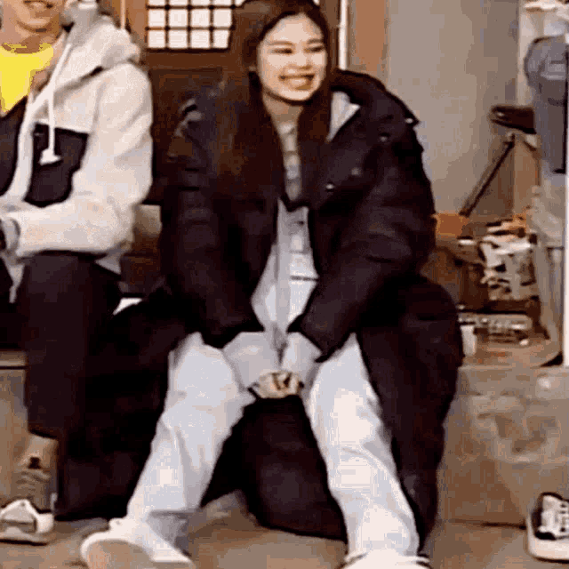 a woman in a black coat is sitting on a couch with her legs crossed .