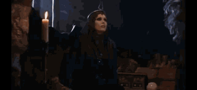 a man in a cape is standing in a room with candles on the wall .