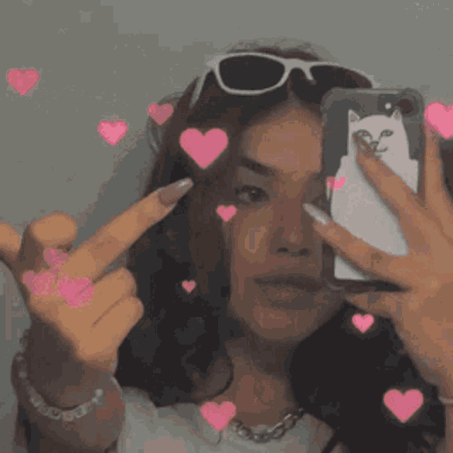 a woman is taking a picture of herself in a mirror with hearts coming out of her hair .
