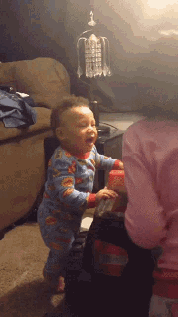a baby wearing a superman pajama is standing in a living room