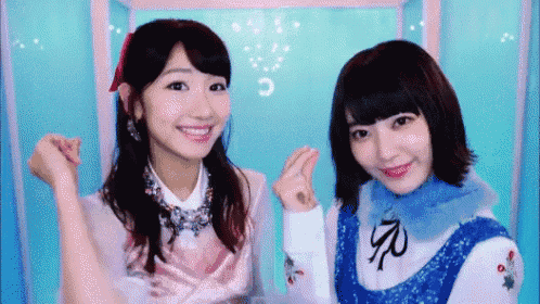 two girls are standing next to each other with their hands in the air .