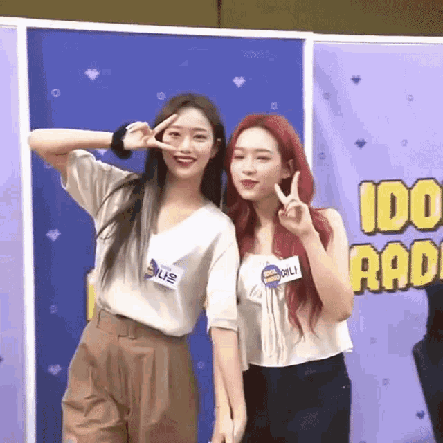 two girls are posing for a picture in front of a sign that says ido radio