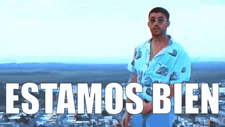 a man is standing in front of a city with the words estamos bien written in white letters