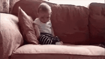 a baby is sitting on a couch with a pillow .