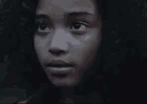 a close up of a young girl 's face with curly hair looking up at the camera .