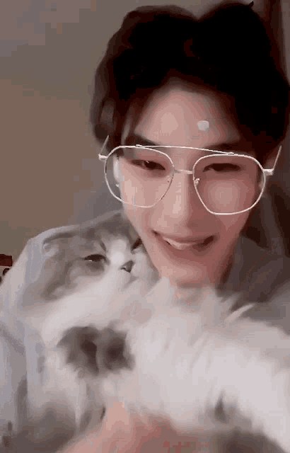 a young man wearing glasses and holding a cat