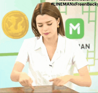 a woman in a white shirt is sitting at a table in front of a sign that says " linemanxfreenbecky "