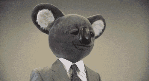 a stuffed koala wearing a suit and tie is making a face .