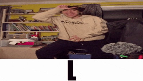 a man wearing a tan avatar hoodie is standing on a chair