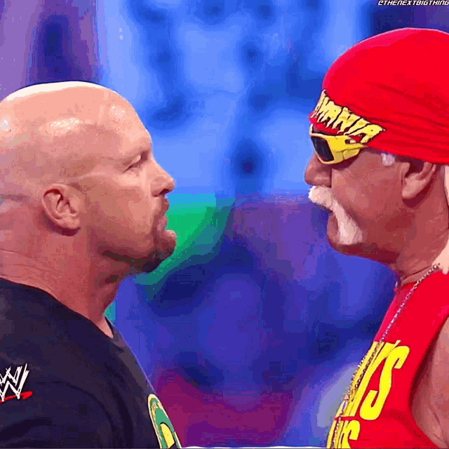 a man wearing a red hat that says ' hulk hogan ' on it stands next to another man