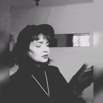 a black and white photo of a woman wearing a hat and necklace