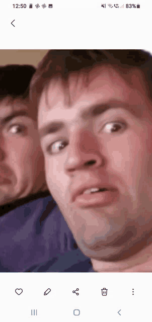 a phone screen shows a man making a funny face and the time 12:50