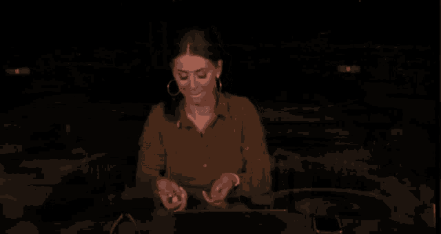 a woman in a brown shirt is sitting at a desk with a laptop