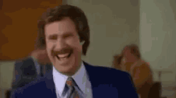 a man in a suit and tie is laughing while sitting in a chair .