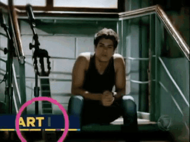 a man sits on a set of stairs next to a pink circle that says art i