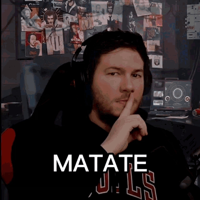 a man wearing headphones and a chicago bulls shirt holds his finger to his mouth