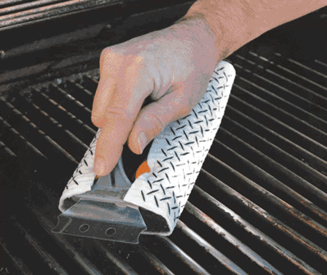 a person is cleaning a grill with a spatula that says ' stainless steel ' on it