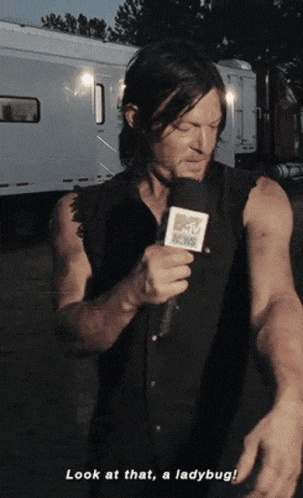 a man holding a mtv news microphone says look at that ladybug