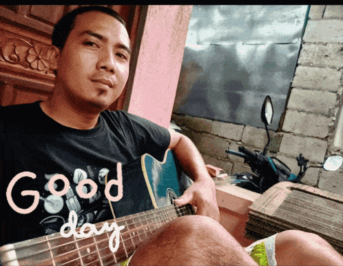 a man wearing a black shirt that says good day is playing a guitar