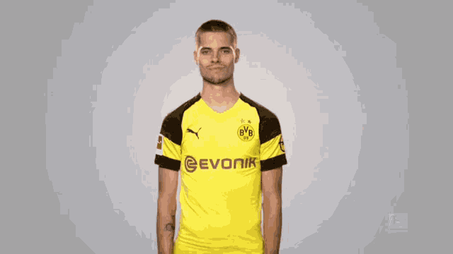 a man wearing a yellow evonik jersey stands with his hands in his pockets