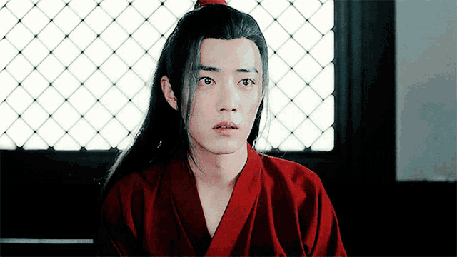 a man with long hair is wearing a red robe