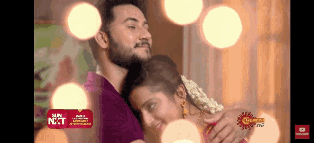 a man and a woman are hugging each other with a sun nxt ad in the background