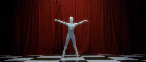 a group of ballerinas are dancing on a checkered floor in front of a red curtain .