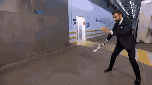 a man in a suit is holding a sword in front of a wall that says 28