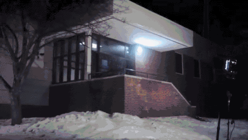 a brick building is lit up at night with snow on the ground in front of it