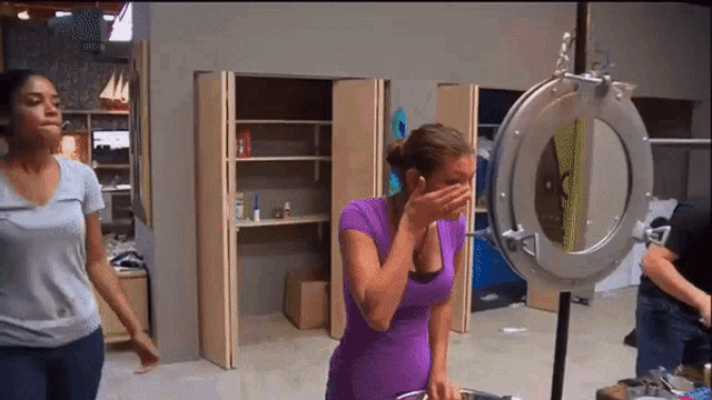 a woman in a purple shirt is covering her mouth